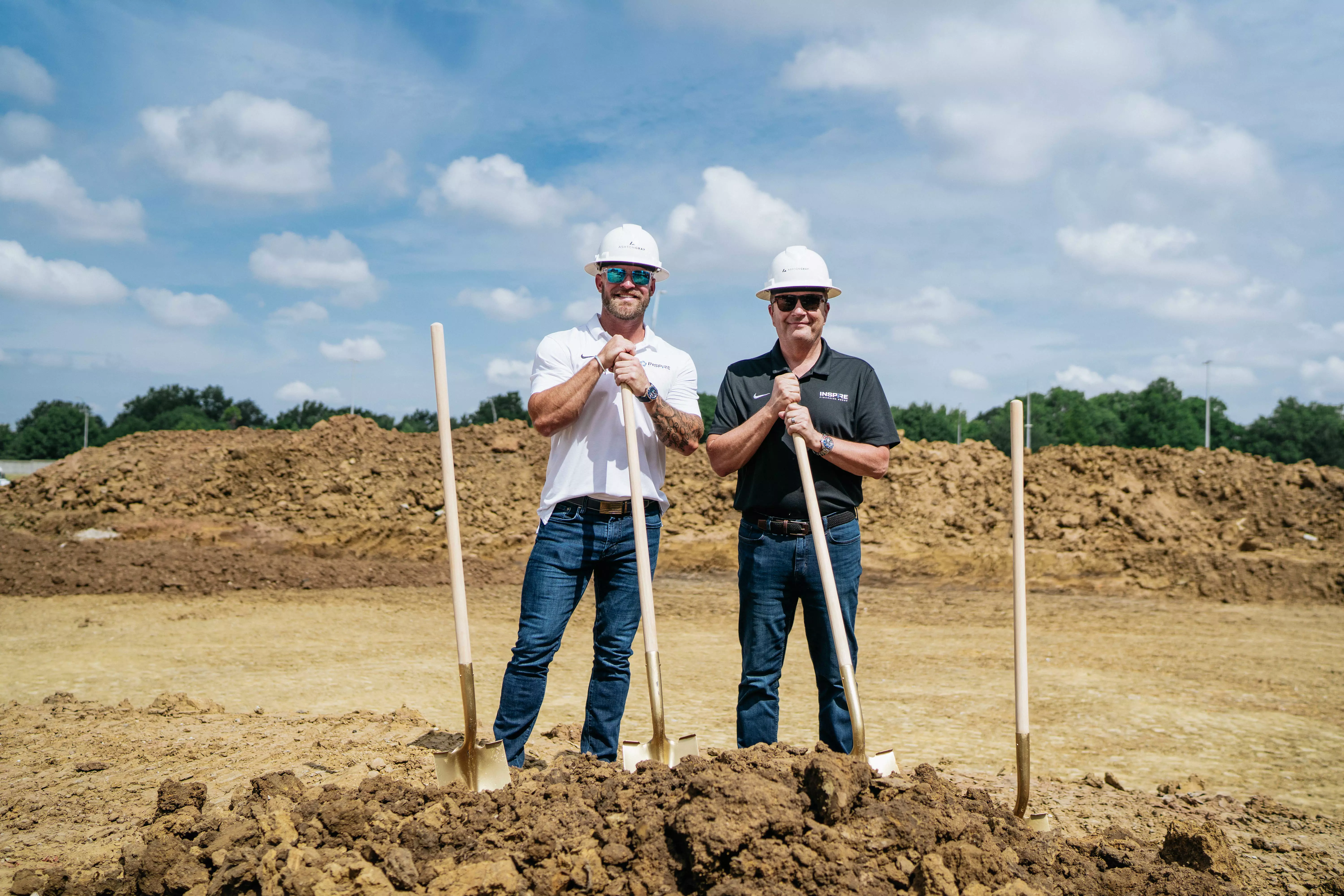 Construction site groundbreaking event with a dozer and golden shovels